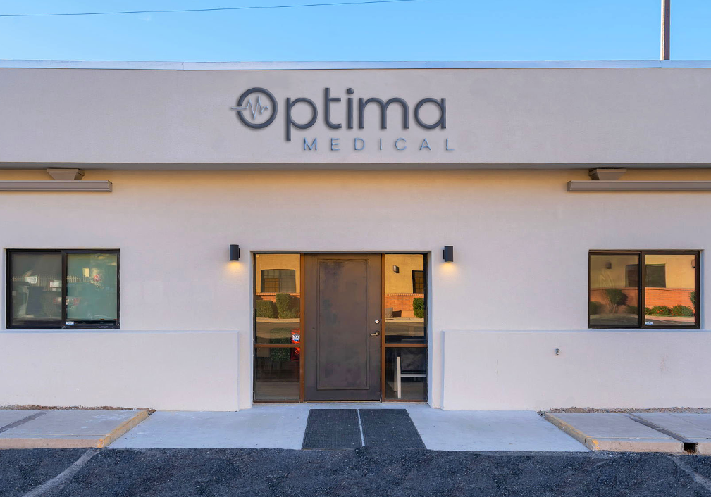 Exterior of Optima Medical primary care clinic at 5902 East Pima Street in Tucson, Arizona, featuring building front with brown entrance door and Optima Medical signage.