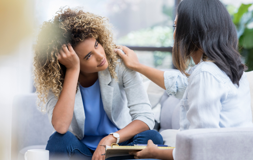 Optima Medical patient with curly hair receives compassionate support from a clinician in an office.