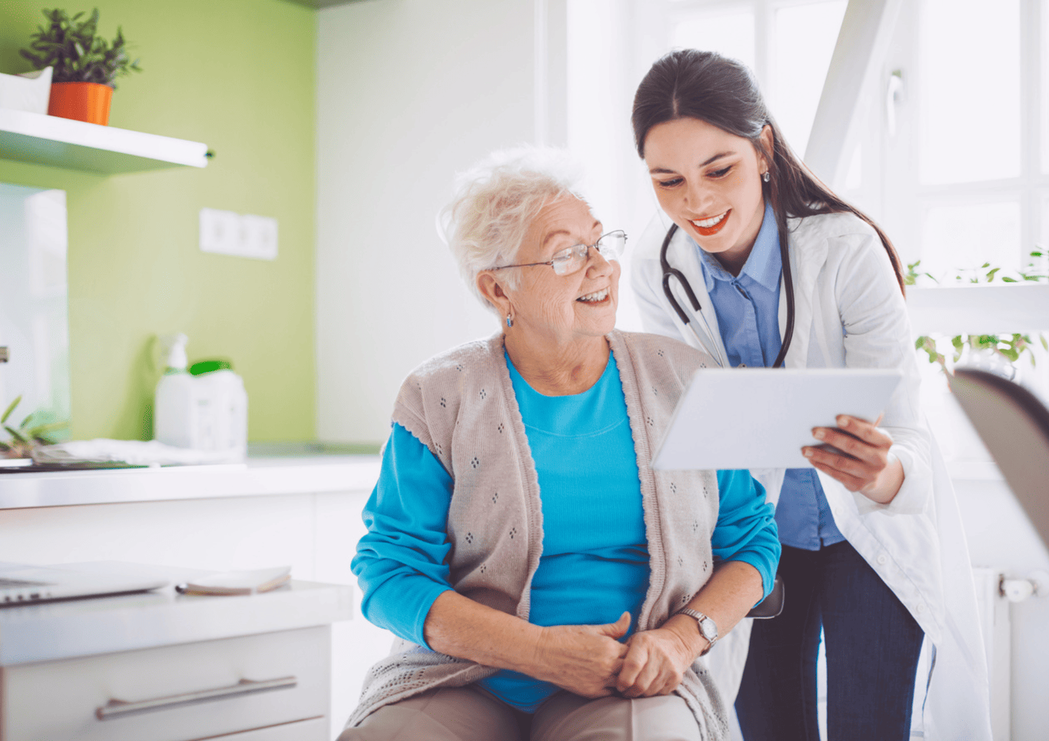 Smiling doctor showing digital health information to a senior patient during a care management visit at Optima Medical clinic in Arizona.