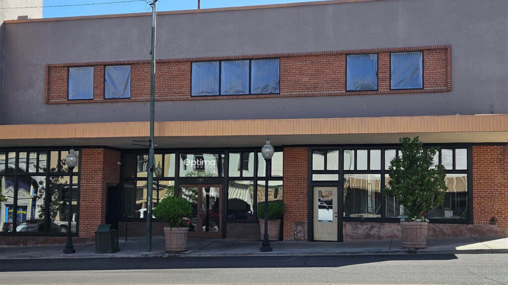 Optima Medical primary care clinic in Globe, Arizona, located in a brick-front building on North Broad Street with large windows and potted plants by the entrance.